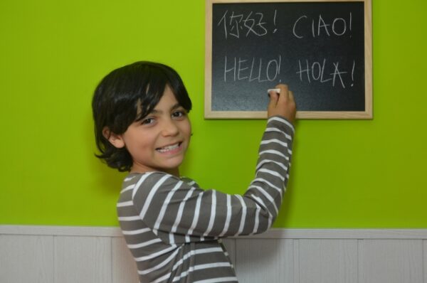 黒板に何か書いて微笑む少年