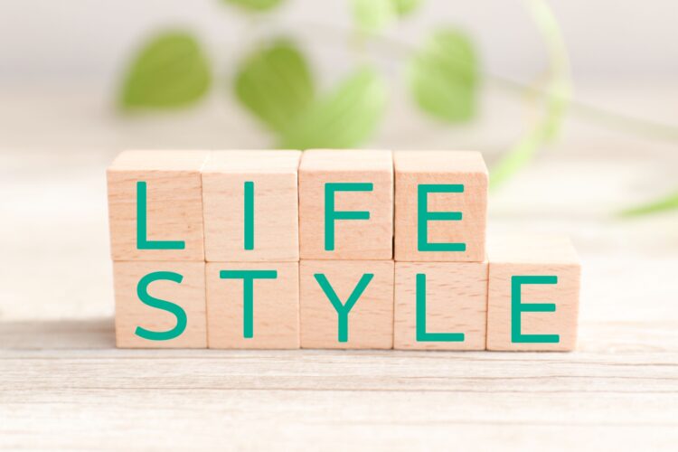木のブロックに「LIFE STYLE」と並んだ文字。明るい木目の背景に、緑の葉っぱがやさしく映っている。