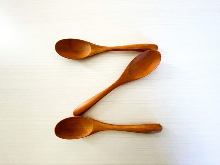 木のスプーン3本が「Z」の形に並べられている。シンプルな白い背景に、自然素材のあたたかさが引き立っている。
