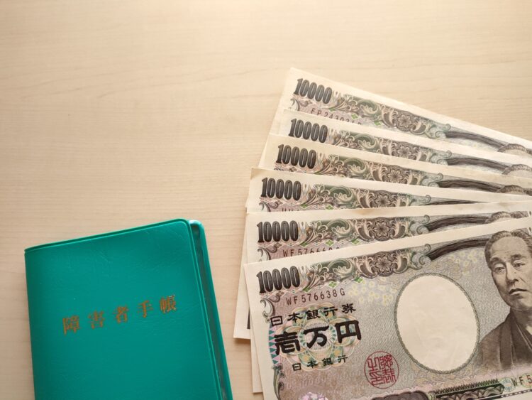 木の机の上に、障害者手帳と1万円札が7枚並べられている。