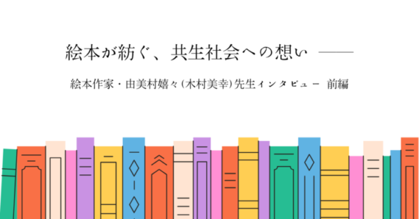 カラフルな本が横一列に並ぶイラストを背景に、中央にタイトル「絵本が紡ぐ、共生社会への想い ――」と書かれている。 その下に「絵本作家・由美村嬉々（木村美幸）先生インタビュー 前編」と記され、温かみのある絵本特集のアイキャッチ画像となっている。