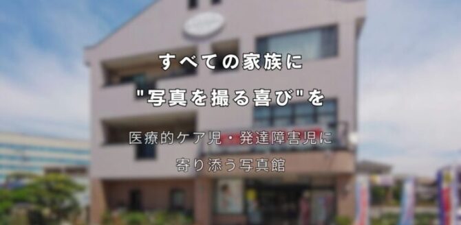 3階建ての建物を背景に、中央に白い文字でキャッチコピーが書かれている。 上部の文字は「すべての家族に “写真を撮る喜び”を」。 その下には「医療的ケア児・発達障害児に寄り添う写真館」と書かれている。 建物の外観は淡いベージュ色で、正面に大きな窓と看板があり、晴れた青空の下で撮影されている。 障害や医療ケアが必要な子どもたちと家族に、写真撮影の楽しさを届ける想いを表現したメインビジュアル。