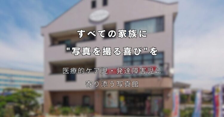 3階建ての建物を背景に、中央に白い文字でキャッチコピーが書かれている。 上部の文字は「すべての家族に “写真を撮る喜び”を」。 その下には「医療的ケア児・発達障害児に寄り添う写真館」と書かれている。 建物の外観は淡いベージュ色で、正面に大きな窓と看板があり、晴れた青空の下で撮影されている。 障害や医療ケアが必要な子どもたちと家族に、写真撮影の楽しさを届ける想いを表現したメインビジュアル。