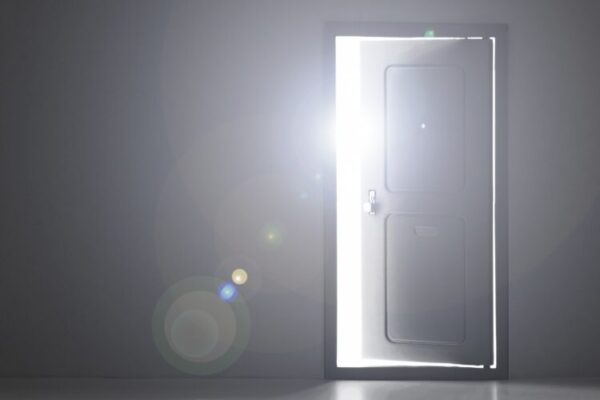 暗がりの中で、扉が少し開き、まぶしい光が差し込んでいる。 新しい一歩や希望の始まりをそっと感じさせる情景。