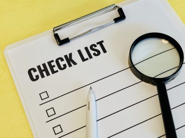  「CHECK LIST」と書かれた紙が挟まったクリップボードと、虫眼鏡、ペンが並んだイメージ写真。